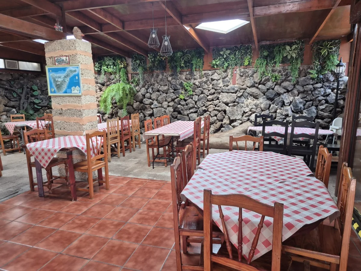 Salón de La Carreta del Carretón, con su pared de piedra volcánica y las mesas vestidas